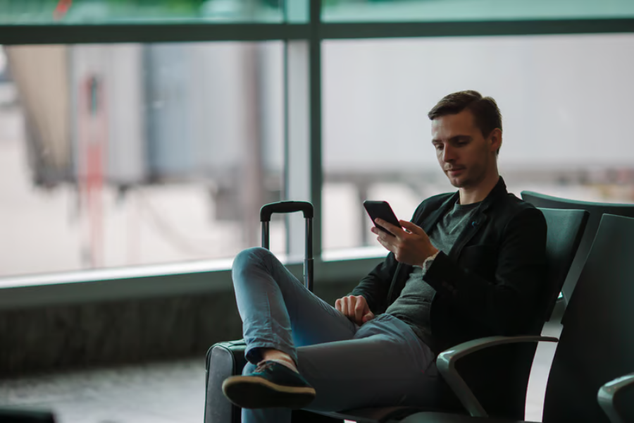 Wisatawan menggunakan smartphone untuk mengakses internet selama perjalanan internasional dengan paket konektivitas yang sesuai.