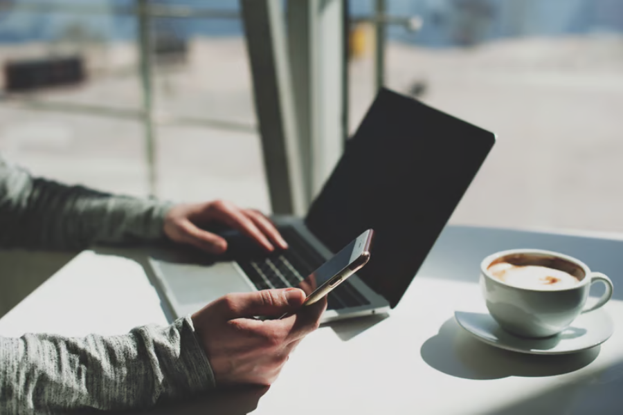 wisatawan menggunakan laptop dan ponsel di kafe dengan memperhatikan keamanan koneksi wifi publik